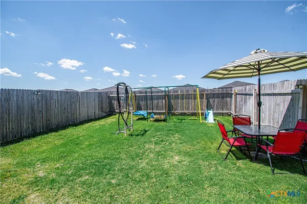 a view of a backyard with table and chairs under an umbrella