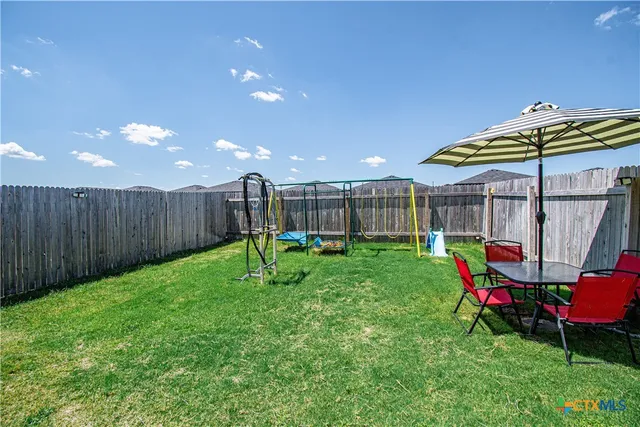 a view of a backyard with table and chairs under an umbrella