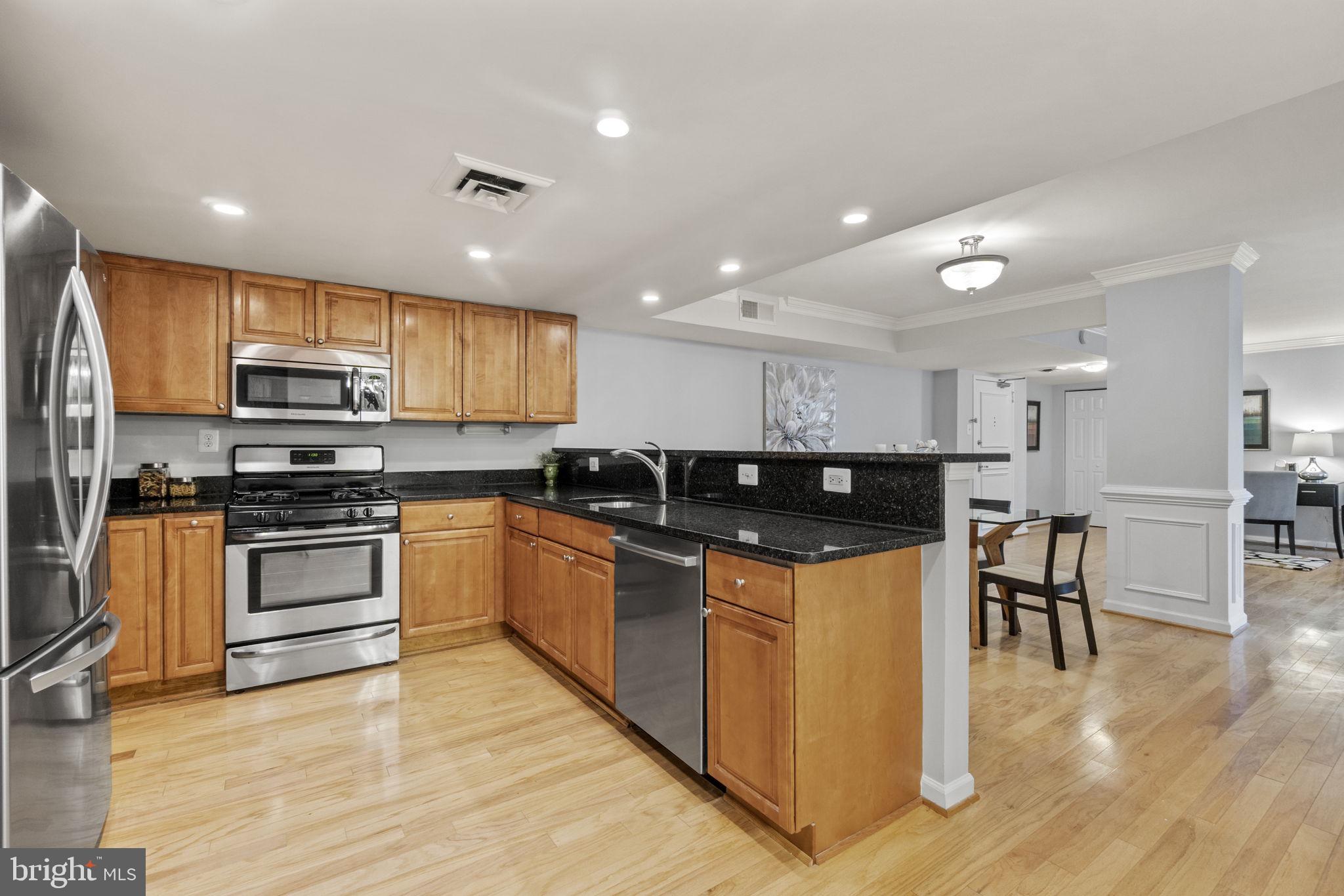1515 South Arlington Ridge Road, Unit 603 Arlington, VA 22202 - Photo 4 of 22 a kitchen with stainless steel appliances granite countertop a stove top oven a sink dishwasher a refrigerator and a dining table with wooden floor