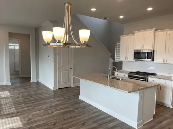 a kitchen with stainless steel appliances granite countertop a sink a stove and a wooden floors