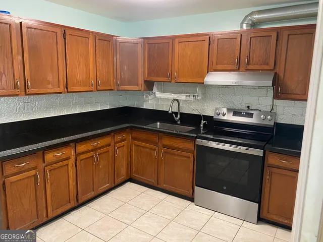 a kitchen with granite countertop cabinets sink and white appliances