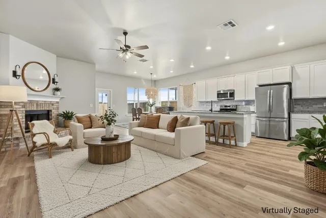 a kitchen with stainless steel appliances granite countertop a refrigerator a stove a sink a microwave and white cabinets with wooden floor