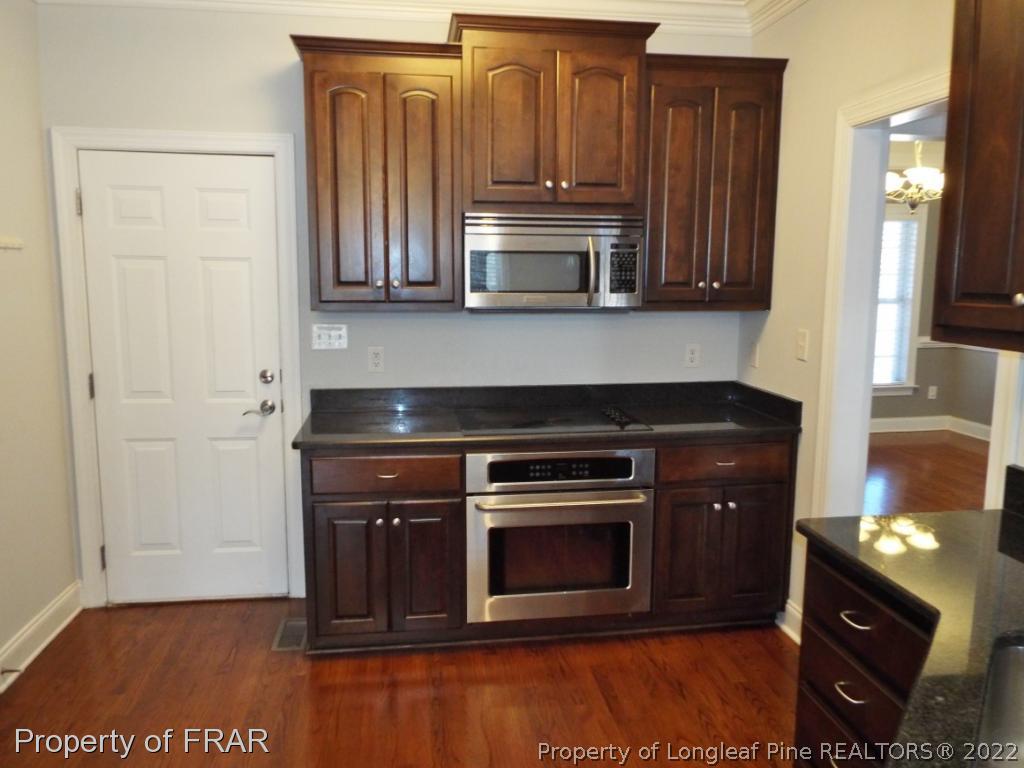 239 Falling Water Road Spring Lake, NC 28390 - Photo 18 of 36 a kitchen with granite countertop a stove and a microwave with wooden floor