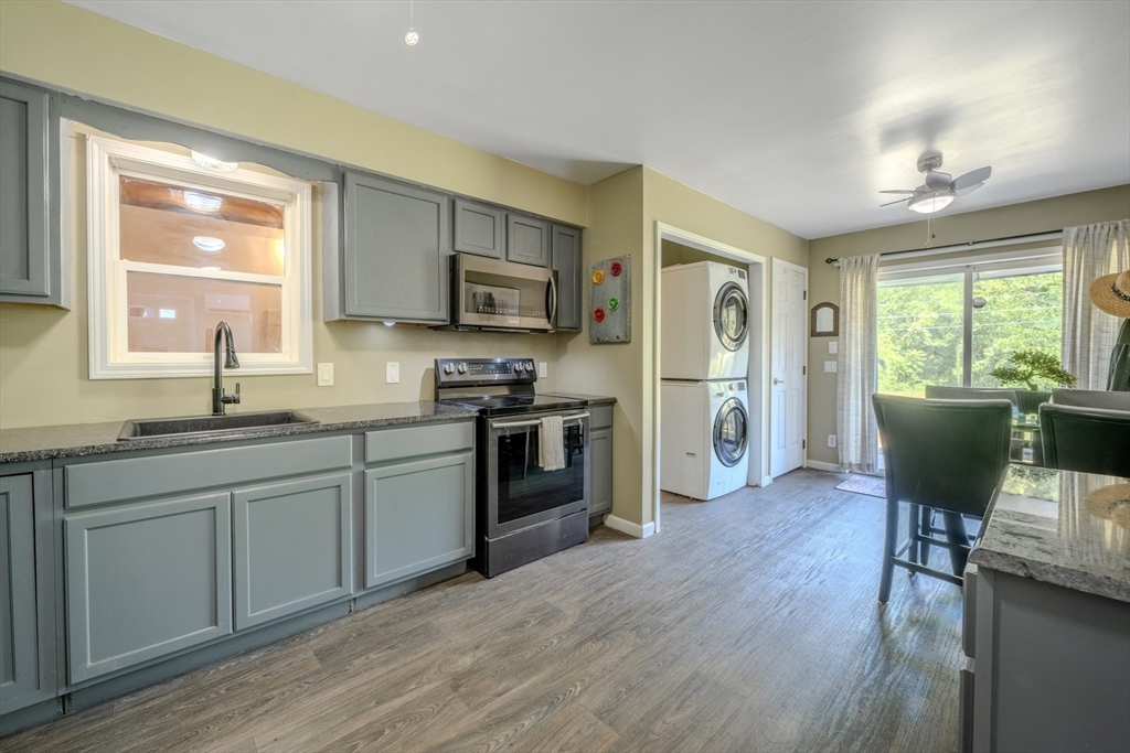 66 Great Road Shirley, MA 01464 - Photo 7 of 40 a kitchen with stainless steel appliances granite countertop a refrigerator a stove top oven a sink dishwasher and white cabinets with wooden floor