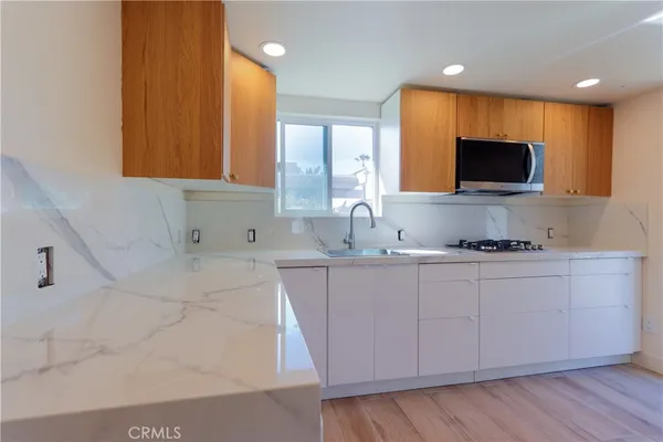 a large kitchen with stainless steel appliances a large counter top and a wooden floor