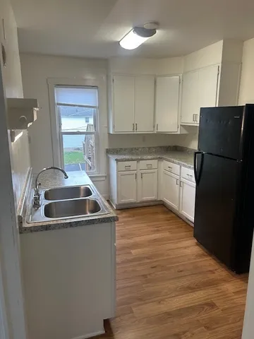 a kitchen with stainless steel appliances granite countertop a sink a stove a refrigerator a washer dryer and white cabinets