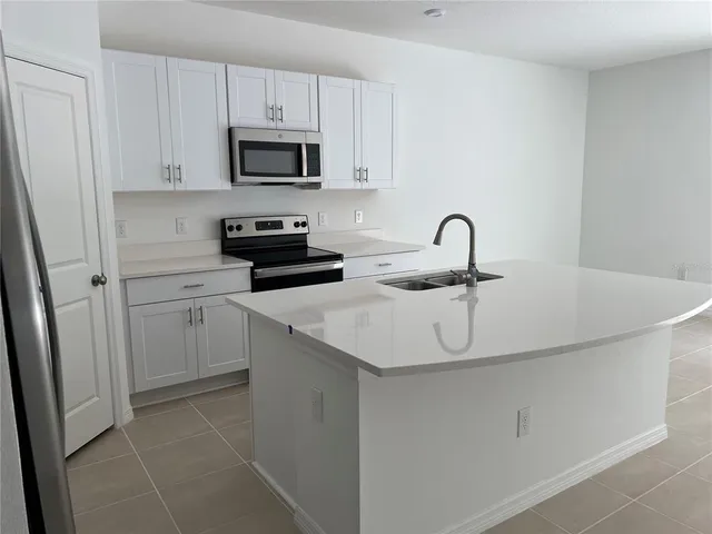 a kitchen with white cabinets a sink and appliances