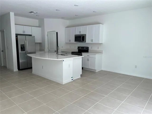 a kitchen with stainless steel appliances a sink a stove a refrigerator cabinets and a counter top space