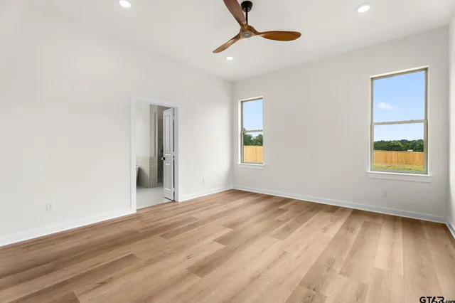 a view of an empty room with window and wooden floor