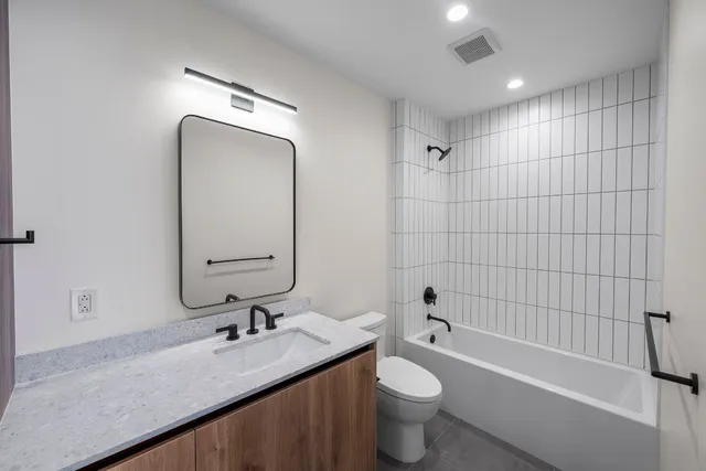 a bathroom with a bathtub shower sink mirror vanity and toilet
