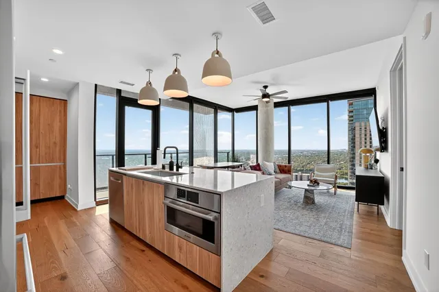 a very nice looking living room with a large window wooden floor and stainless steel appliances