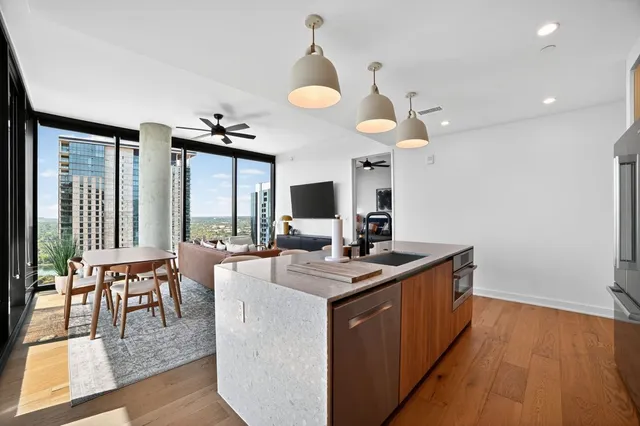 a kitchen with a stove a counter space a sink and living room view