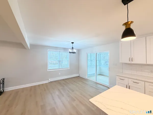 a kitchen with granite countertop a stove a sink and white cabinets with wooden floor