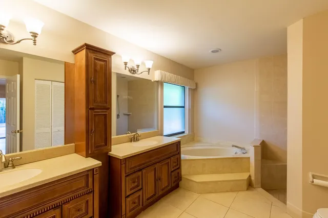a bathroom with a double vanity sink mirror and bathtub