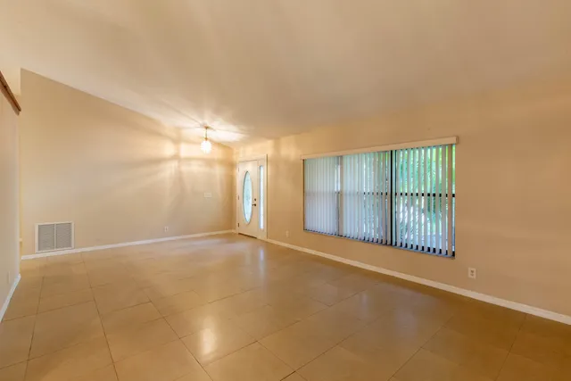 a view of an empty room with wooden floor and fan