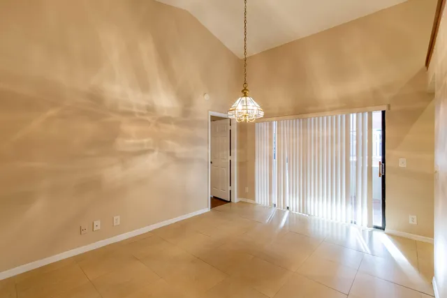 an empty room with a chandelier fan and windows