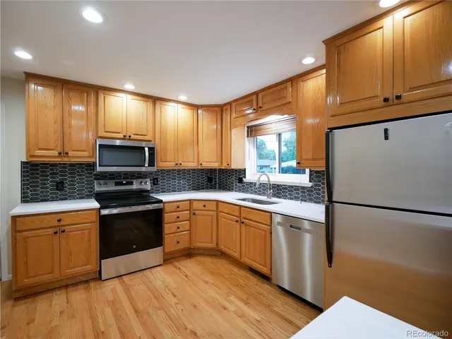 a kitchen with granite countertop a refrigerator stove top oven and sink