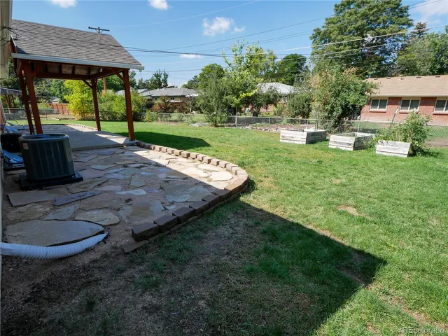a view of a backyard with table and chairs potted plants and large tree