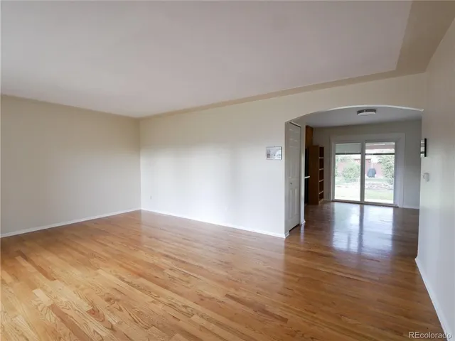 a view of an empty room and wooden floor and a window