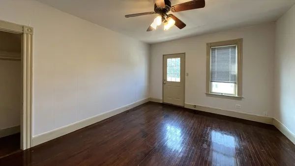 a view of an empty room with wooden floor and a window