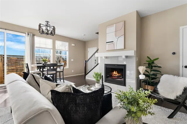 a living room with furniture potted plant floor to ceiling window and a fireplace