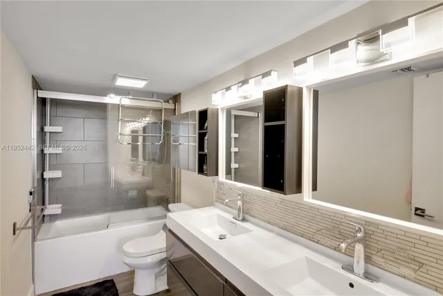 a bathroom with a bathtub shower sink mirror vanity and toilet