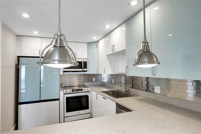 a kitchen with stainless steel appliances a sink a stove a refrigerator and cabinets