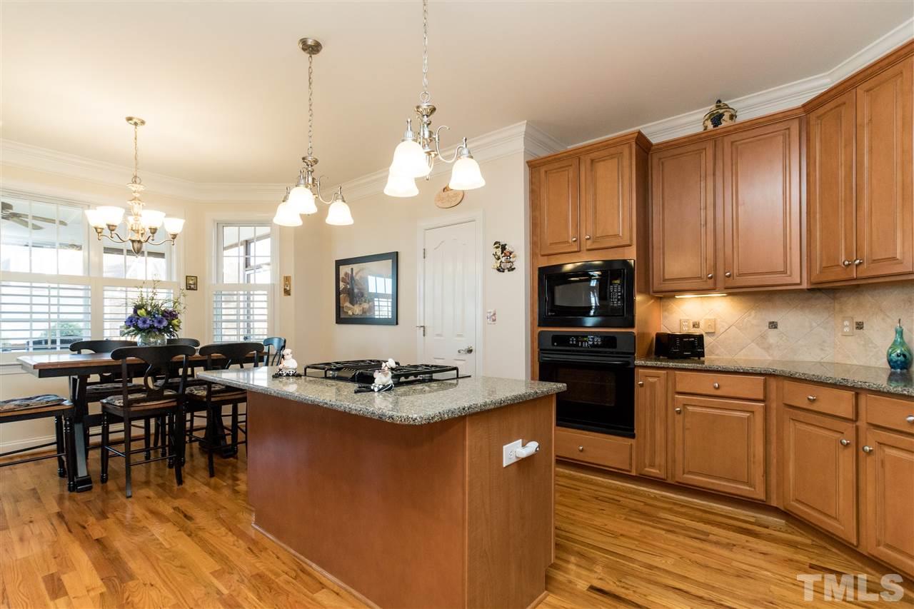 322 Challenge Road Raleigh, NC 27603 - Photo 8 of 25 a kitchen with kitchen island granite countertop a stove a sink a dining table and chairs with wooden floor