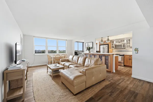 a living room with furniture kitchen and a wooden floor