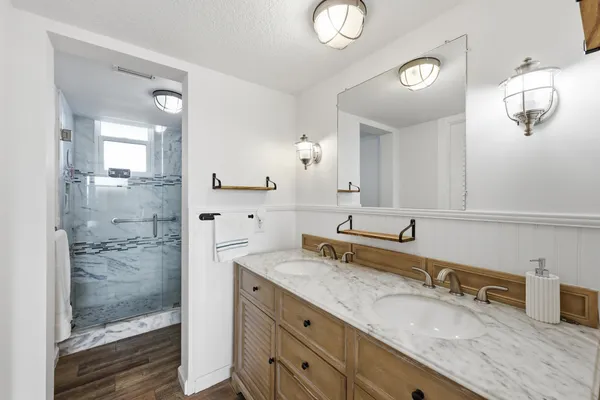 a bathroom with a granite countertop sink a mirror and shower