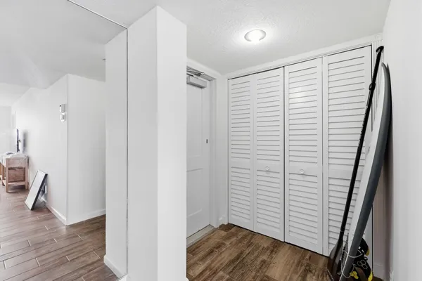 a view of a hallway with wooden floor and closet