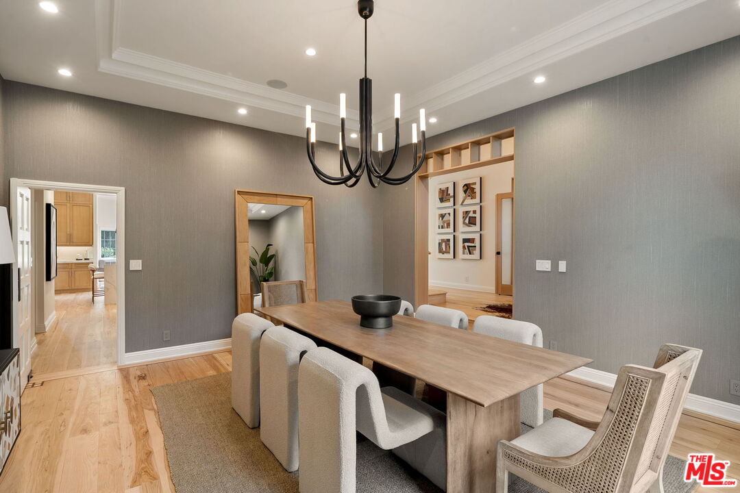 280 Homewood Road Los Angeles, CA 90049 - Photo 10 of 53 a dining room with wooden floor a chandelier a wooden table and chairs