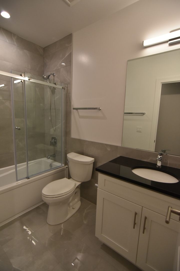 Undisclosed Address Chicago, IL 60613 - Photo 15 of 17 a bathroom with a granite countertop sink a toilet a mirror and shower