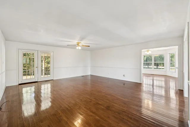 an empty room with wooden floor and windows
