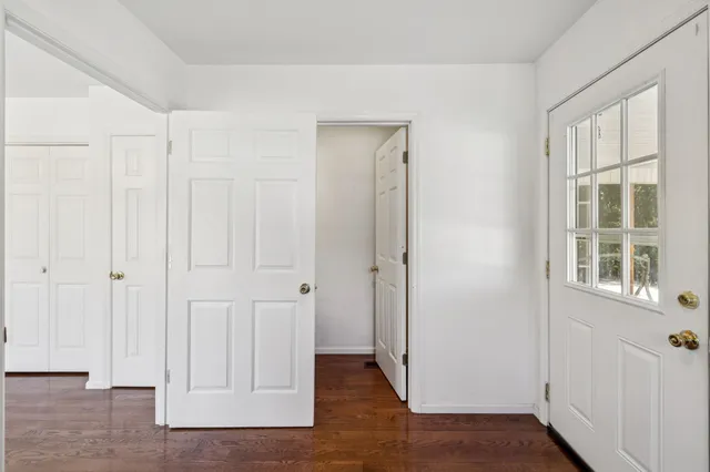 a view of an empty room with window wooden floor and a chandelier fan