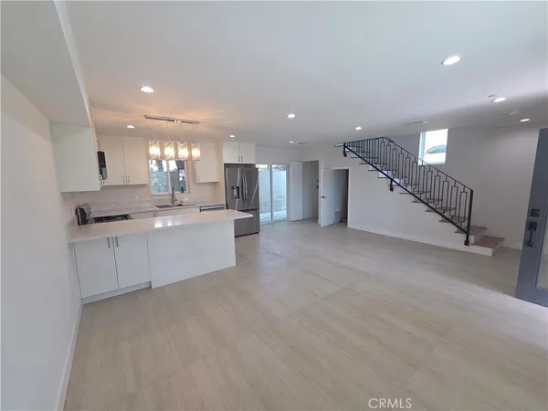 a large white kitchen with a refrigerator a sink and a stove top oven