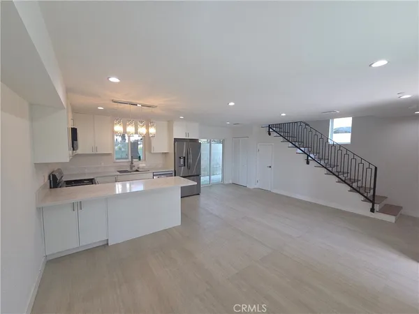 a large kitchen with a large counter top a sink stainless steel appliances and cabinets