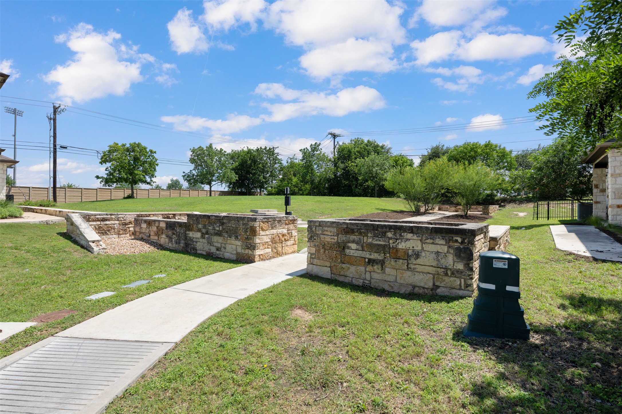211 Parable Cove Pflugerville, TX 78660 - Photo 39 of 40 Grassed outdoor area with stone-clad retaining walls, concrete pathways, and mature trees