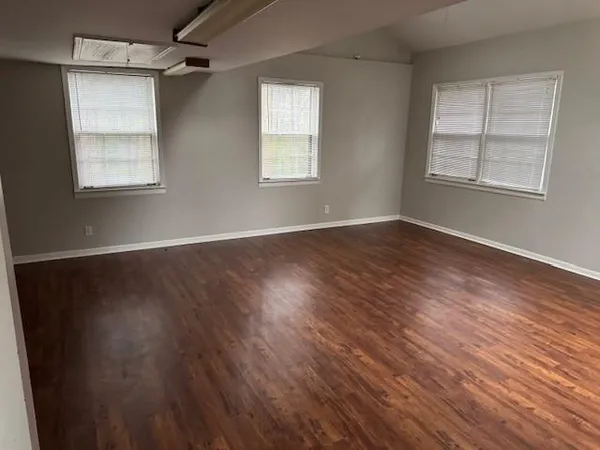an empty room with wooden floor windows and closet