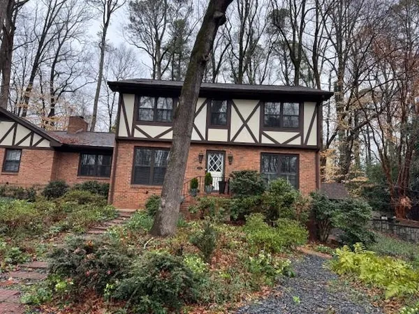 a view of a brick house with a small yard and large trees