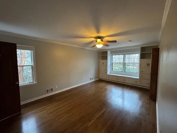 an empty room with wooden floor chandelier and windows