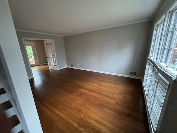 a view of an empty room with wooden floor and a window