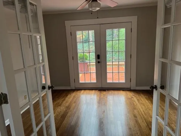 a view of an empty room with a window and wooden floor