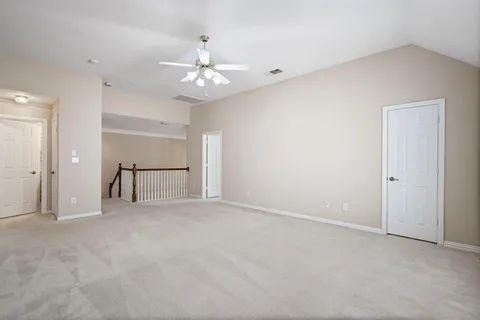 an empty room with chandelier fan and windows