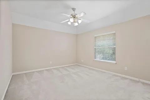 an empty room with windows and chandelier fan