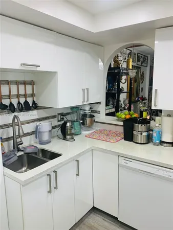 a kitchen with white cabinets and sink