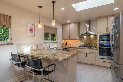 a kitchen with stainless steel appliances granite countertop a stove a sink and a refrigerator