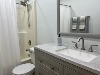 a bathroom with a granite countertop sink vanity mirror and toilet