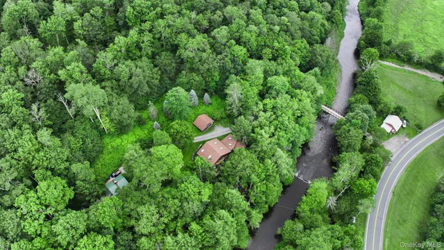 an aerial view of residential house with outdoor space and trees all around