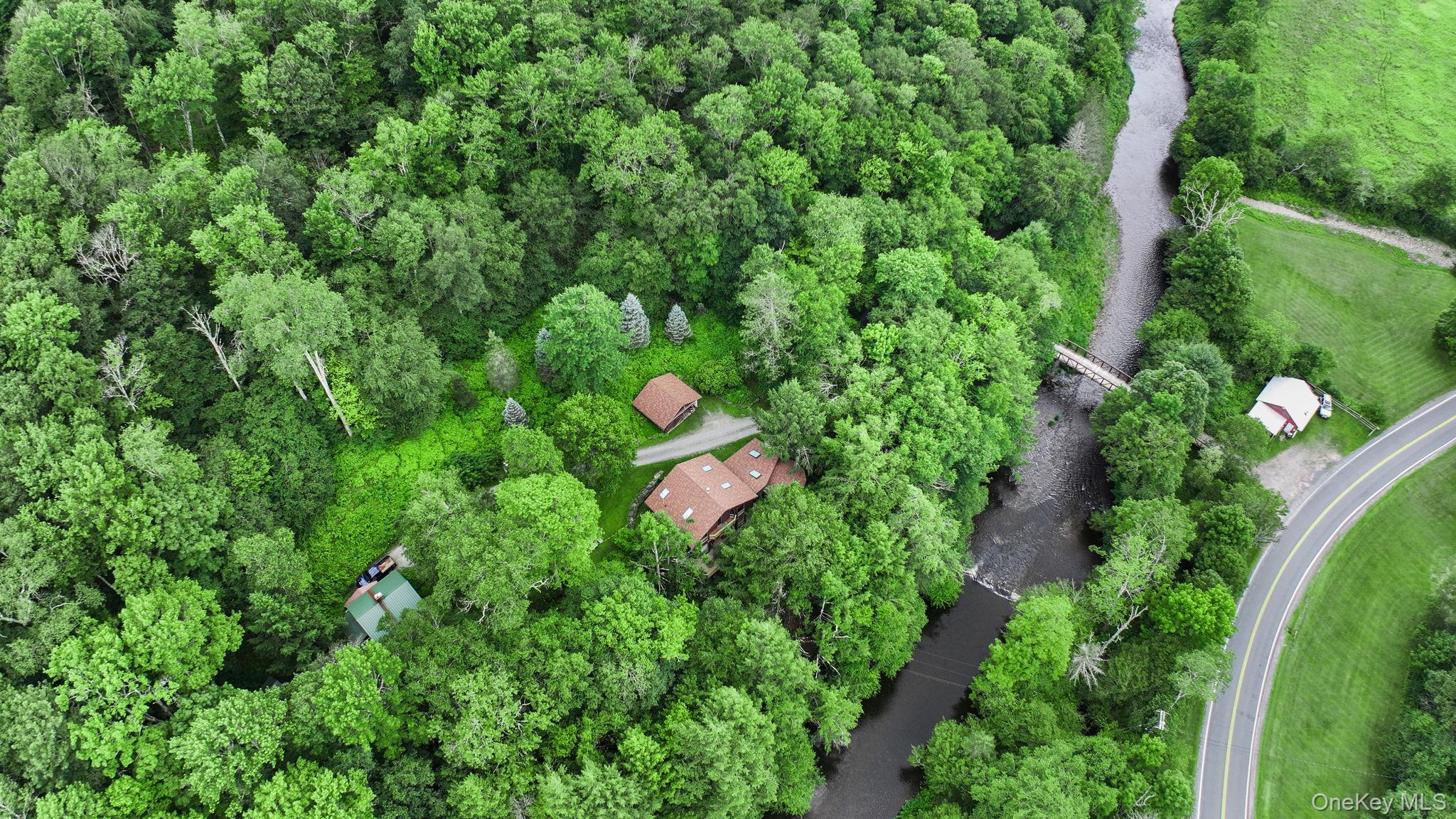 an aerial view of residential house with outdoor space and trees all around